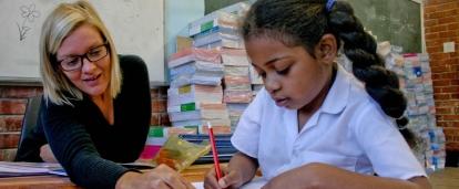 A Projects Abroad volunteer teaching in South Africa helps a young girl with her homework A student receives homework help from a volunteer working as a teacher in South Africa